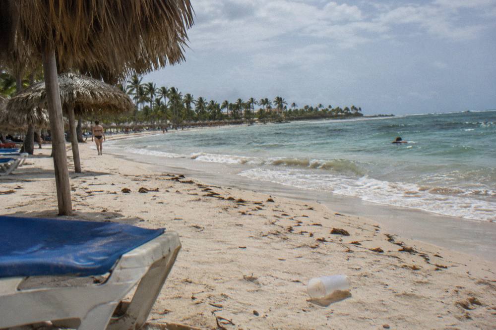 Quiet stretch of Bávaro beach with thatched umbrellas and gentle surf at midday